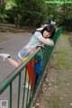 A woman leaning against a fence with an umbrella.