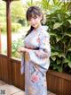 A woman in a blue kimono standing on a wooden deck.