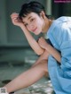 A woman in a blue shirt and white shoes sitting on the ground.