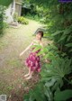 A woman in a purple dress standing in a garden.