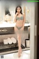 A woman in a gray lingerie standing in front of a mirror.