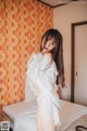 A woman in a white shirt is posing on a bed.