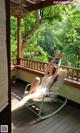 A woman sitting in a rocking chair on a porch.