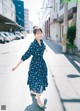 A woman in a blue dress is walking down the street.