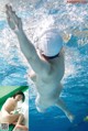 A naked woman in a swimming pool with her arms outstretched.