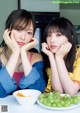 Two young women sitting at a table with a bowl of fruit.