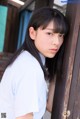 A young woman leaning against a wooden door.