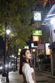 A woman standing on a city street at night.