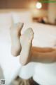 A woman's bare feet on a bed in a bedroom.